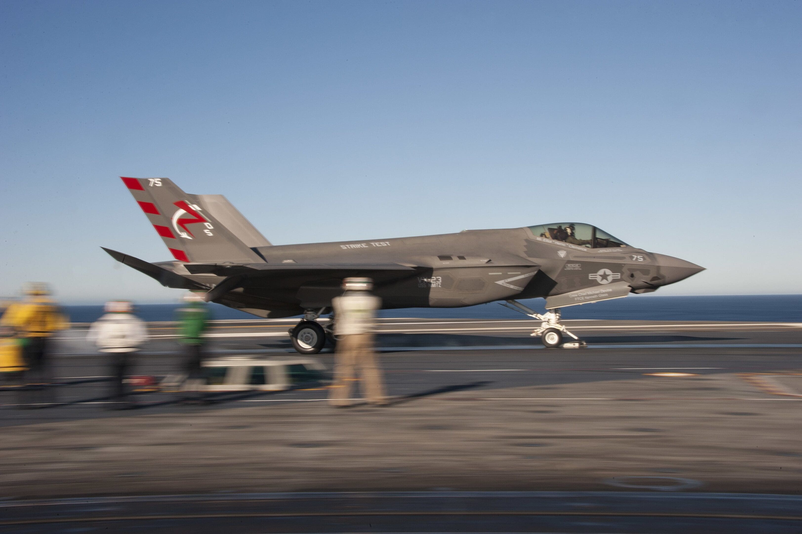 A jet fighter plane on the runway of an airport.