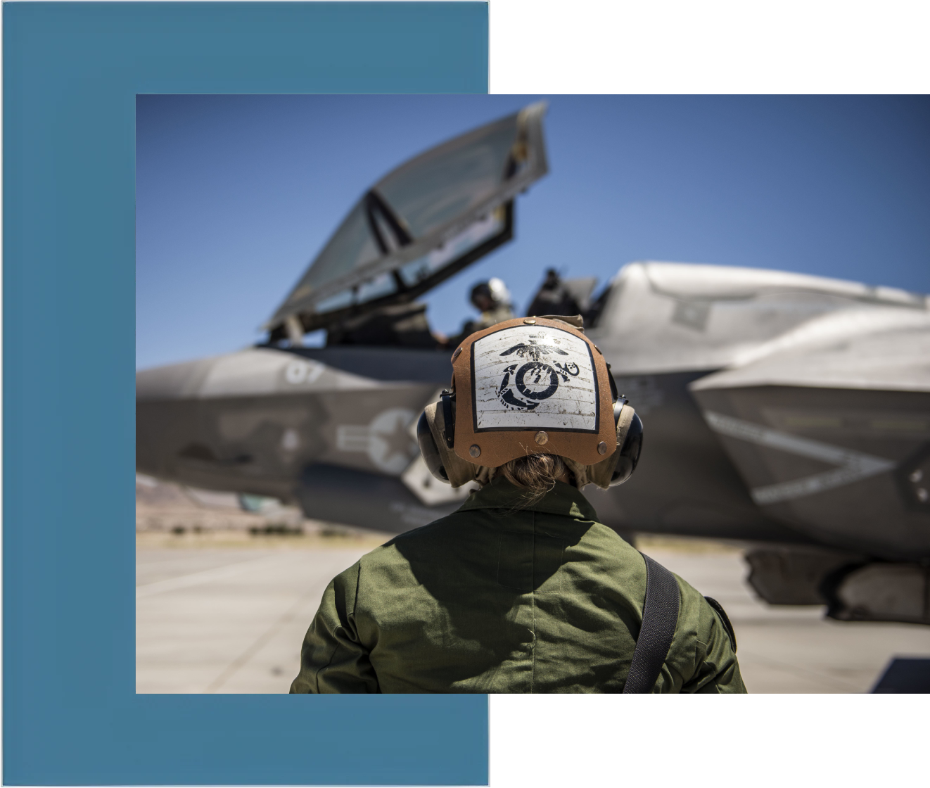 A man in green jacket looking at an airplane.