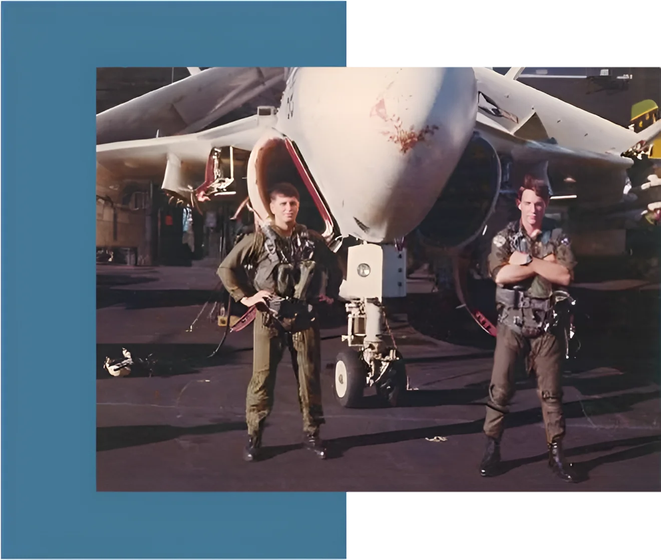 Two men standing in front of a fighter jet.