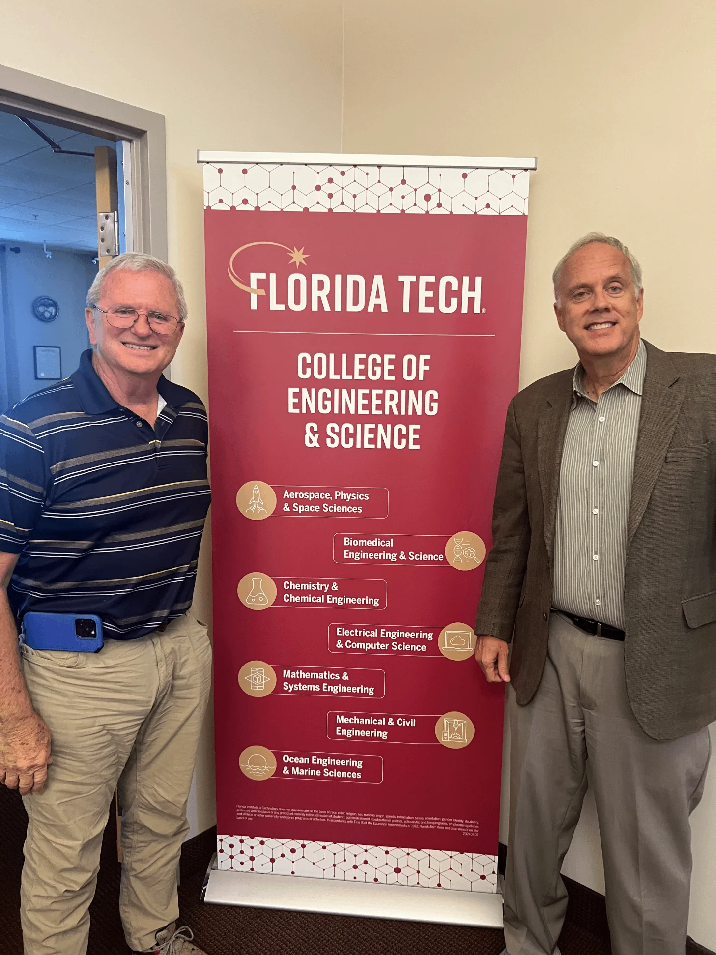 Two men standing next to a sign that says florida tech college of engineering and science.